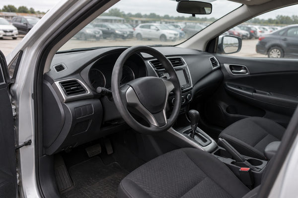 Interior do sedã prata: painel, volante e banco do motorista (foto fictícia de exemplo).