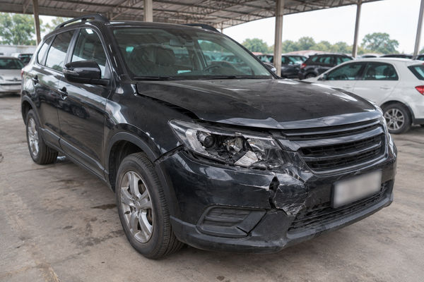SUV preto no pátio do leilão com para-choque dianteiro rachado e farol quebrado (foto fictícia de exemplo).